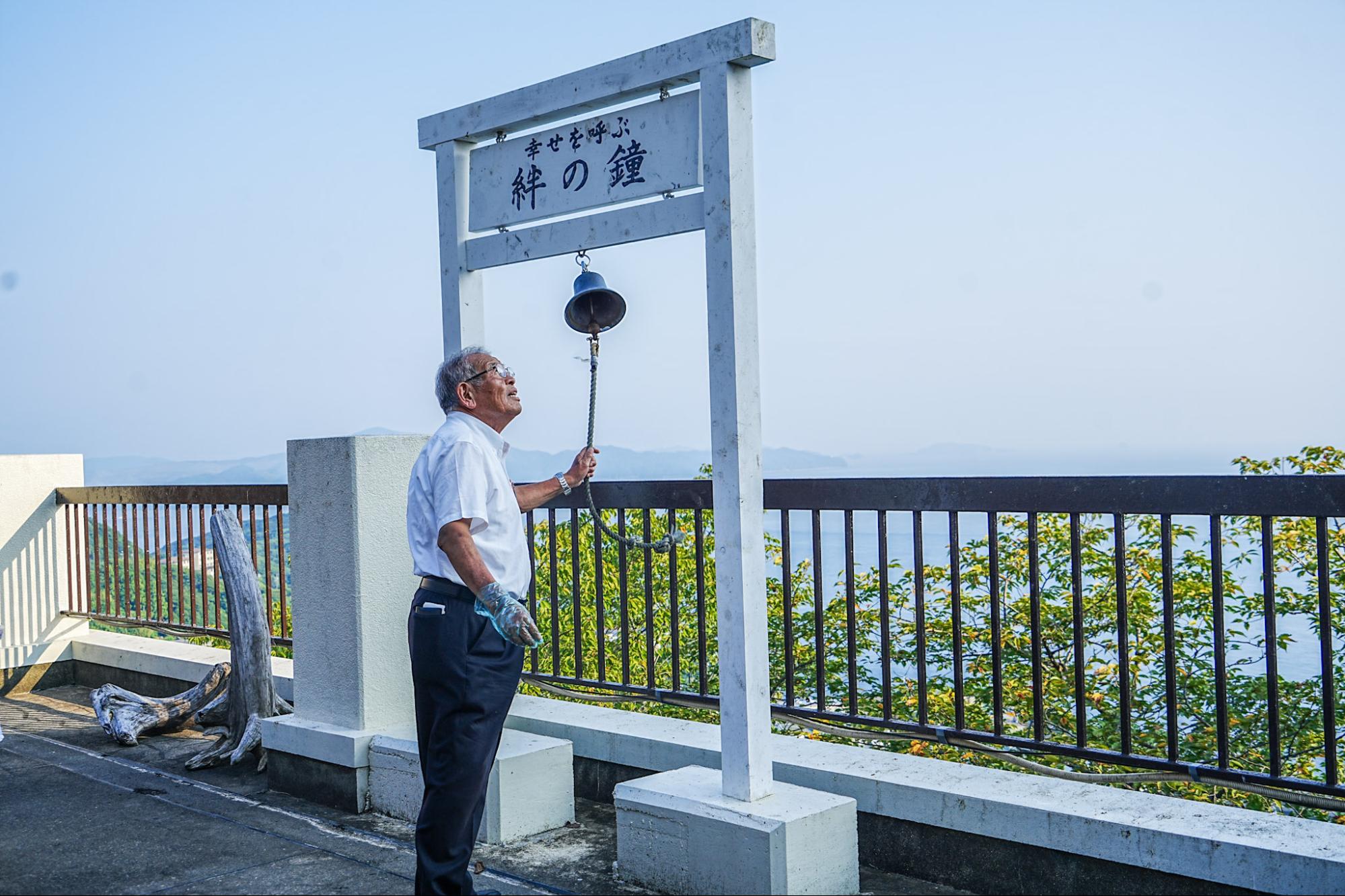 スタッフさんが鐘を鳴らしてトンビを呼ぶ様子